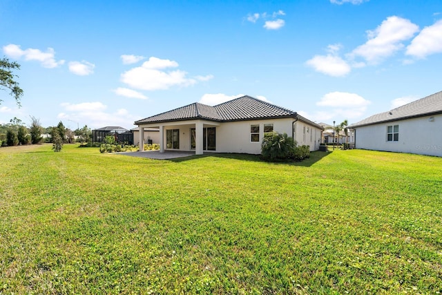 rear view of property featuring a patio, a lanai, and a yard