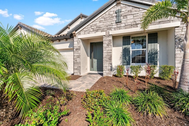 property entrance with an attached garage, stone siding, and stucco siding