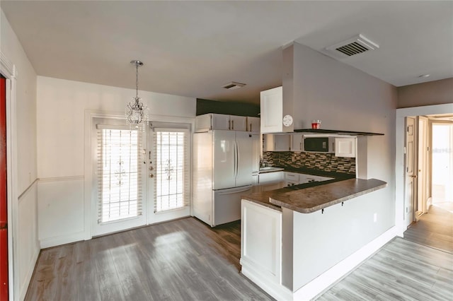 2005 E Crenshaw St, Tampa, FL 33610 - kitchen with white fridge, kitchen peninsula, decorative backsplash, white cabinetry, and decorative light fixtures