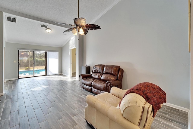 living room with lofted ceiling, a textured ceiling, ceiling fan, and ornamental molding