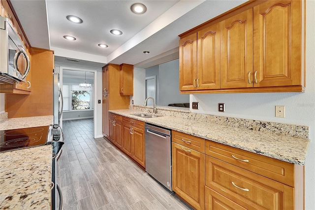 kitchen featuring sink, light hardwood / wood-style flooring, light stone counters, and appliances with stainless steel finishes