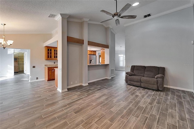 living room featuring ceiling fan with notable chandelier, ornamental molding, and vaulted ceiling