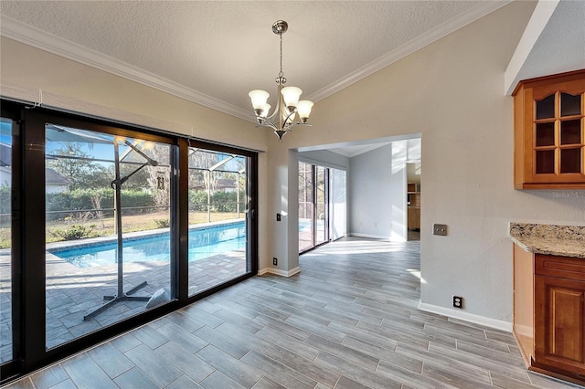 entryway with a textured ceiling, a notable chandelier, and crown molding