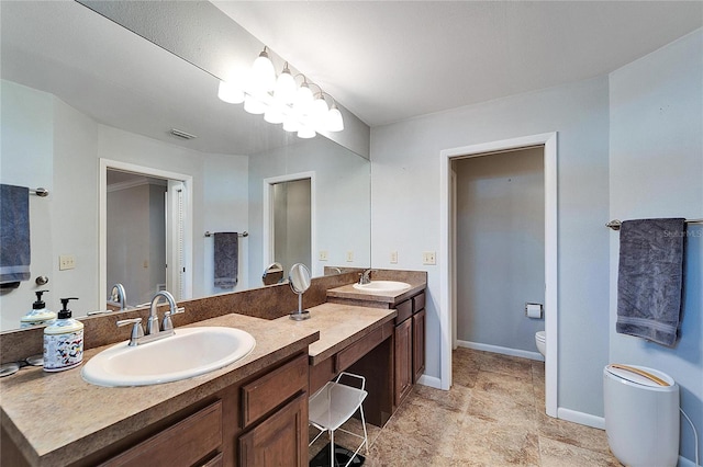 bathroom with a notable chandelier, vanity, and toilet