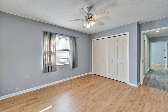 unfurnished bedroom with a textured ceiling, ceiling fan, light hardwood / wood-style flooring, and a closet