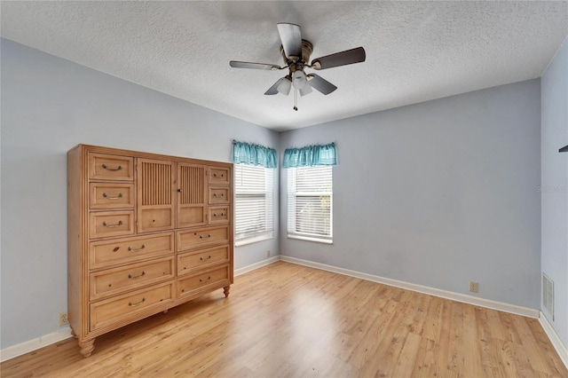 unfurnished bedroom featuring ceiling fan, light wood-type flooring, and a textured ceiling