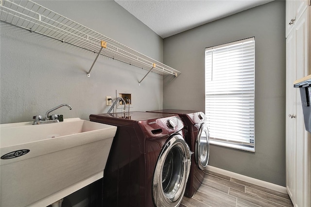 laundry area with sink, washing machine and clothes dryer, and a textured ceiling