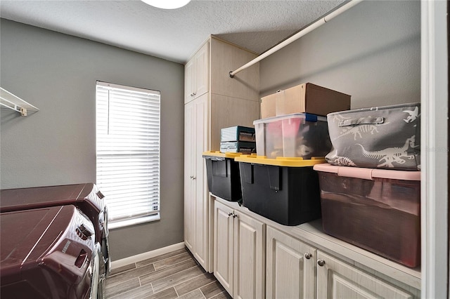 laundry area featuring washing machine and clothes dryer, a textured ceiling, and cabinets