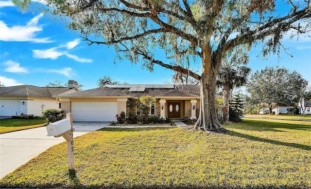 ranch-style home with solar panels, a front lawn, and a garage