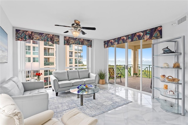 living room featuring ceiling fan and a water view