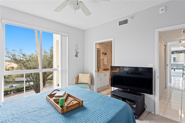 bedroom featuring ceiling fan, light tile patterned floors, and ensuite bath