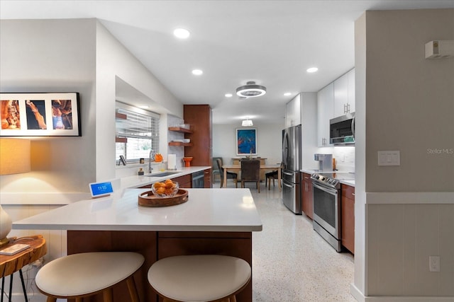 kitchen featuring white cabinets, a kitchen bar, sink, and stainless steel appliances