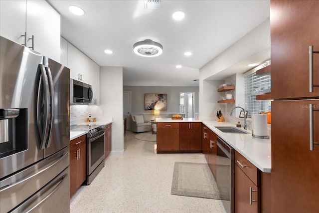 kitchen with white cabinets, appliances with stainless steel finishes, sink, backsplash, and kitchen peninsula