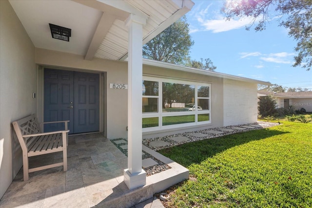 view of exterior entry with a lawn