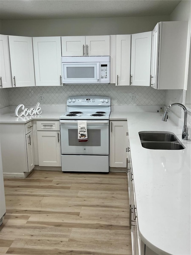 kitchen with white appliances, white cabinetry, and sink