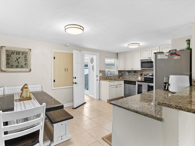 kitchen with sink, light tile patterned floors, stainless steel appliances, white cabinets, and decorative backsplash