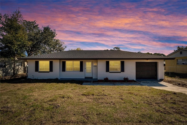 single story home featuring a garage and a lawn