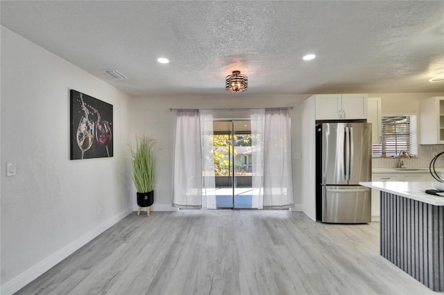 interior space featuring a healthy amount of sunlight, sink, a textured ceiling, and light hardwood / wood-style flooring