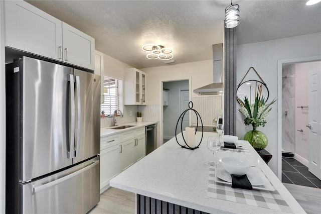 kitchen with appliances with stainless steel finishes, sink, wall chimney range hood, and white cabinets