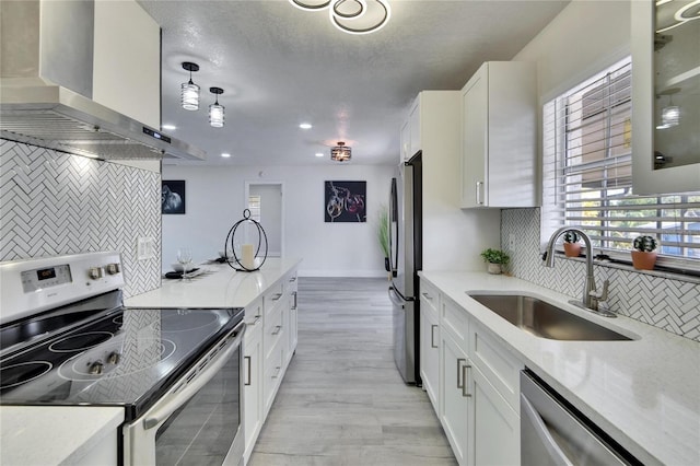 kitchen featuring decorative light fixtures, white cabinetry, sink, island exhaust hood, and stainless steel appliances