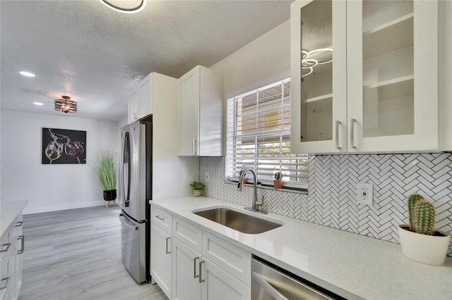 kitchen featuring white cabinetry, stainless steel appliances, sink, and backsplash