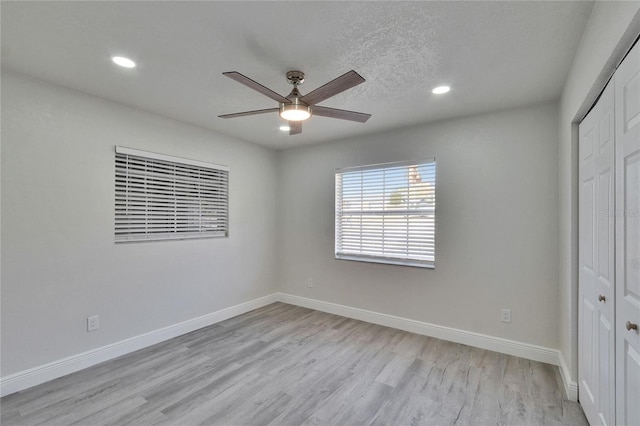 unfurnished bedroom with light wood-type flooring, a textured ceiling, ceiling fan, and a closet