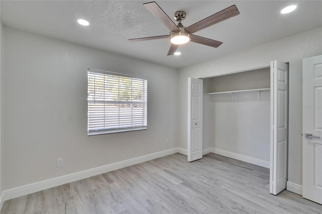 unfurnished bedroom featuring ceiling fan, a closet, and light wood-type flooring