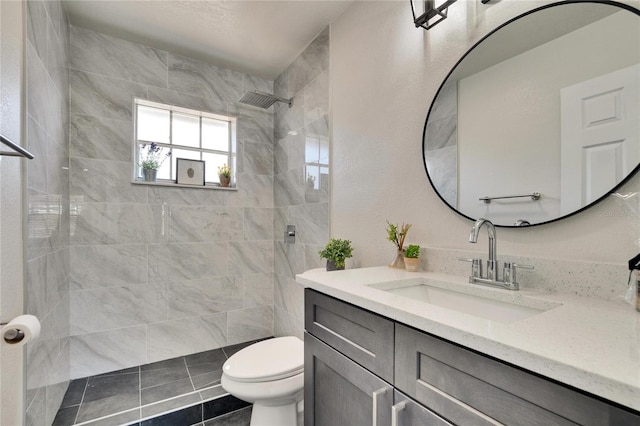 bathroom featuring vanity, tile patterned floors, toilet, and tiled shower