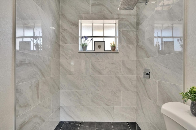 bathroom with toilet and a tile shower