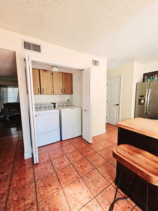 laundry area featuring cabinets, independent washer and dryer, a textured ceiling, and tile patterned flooring