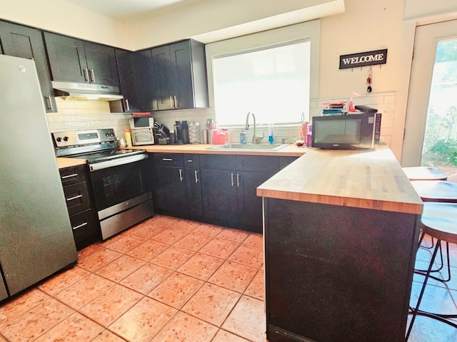 kitchen featuring sink, light tile patterned floors, tasteful backsplash, butcher block countertops, and stainless steel appliances