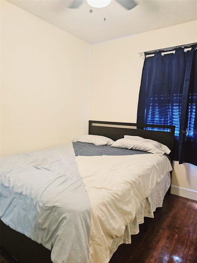 bedroom with a textured ceiling, ceiling fan, and dark hardwood / wood-style floors