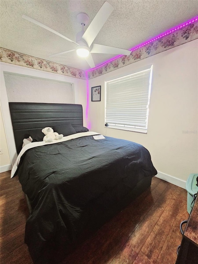 bedroom with ceiling fan, dark wood-type flooring, and a textured ceiling