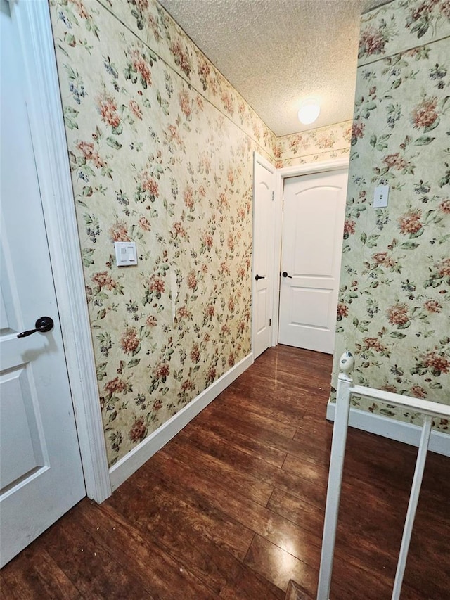 corridor featuring a textured ceiling and dark hardwood / wood-style flooring