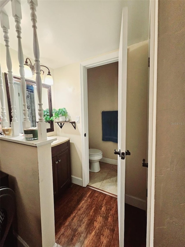 bathroom with toilet, vanity, and hardwood / wood-style flooring