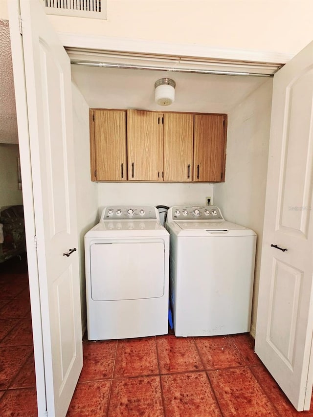 laundry room featuring dark tile patterned flooring, cabinets, and independent washer and dryer