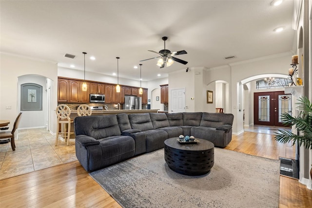 living room featuring ornamental molding, ceiling fan, light wood-type flooring, and french doors