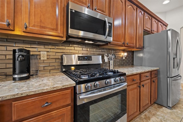 kitchen featuring tasteful backsplash, light tile patterned floors, light stone countertops, and appliances with stainless steel finishes