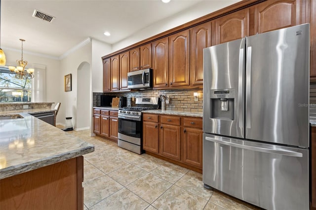 kitchen featuring light stone counters, appliances with stainless steel finishes, a notable chandelier, pendant lighting, and decorative backsplash