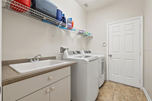 clothes washing area with light tile patterned flooring, washing machine and clothes dryer, sink, and cabinets