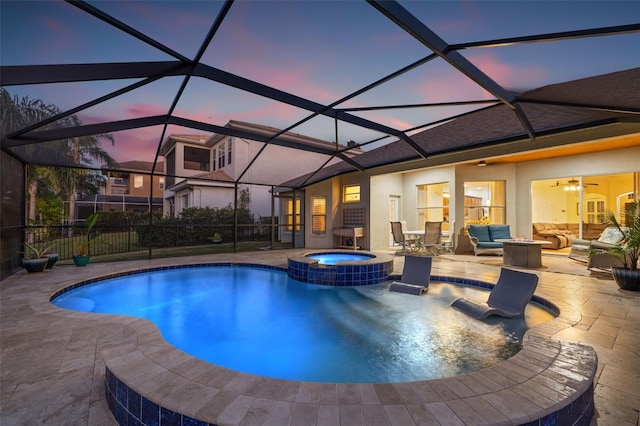 pool at dusk featuring an in ground hot tub, a lanai, an outdoor hangout area, and a patio