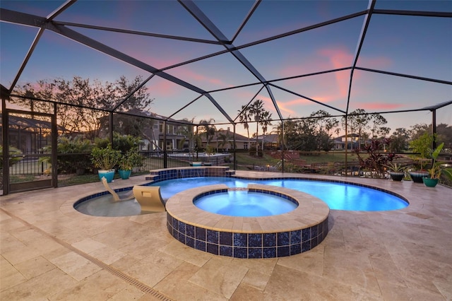 pool at dusk featuring a lanai, a patio area, and an in ground hot tub