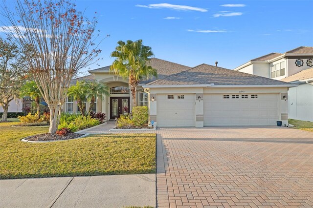 view of front of home with french doors, a garage, and a front lawn