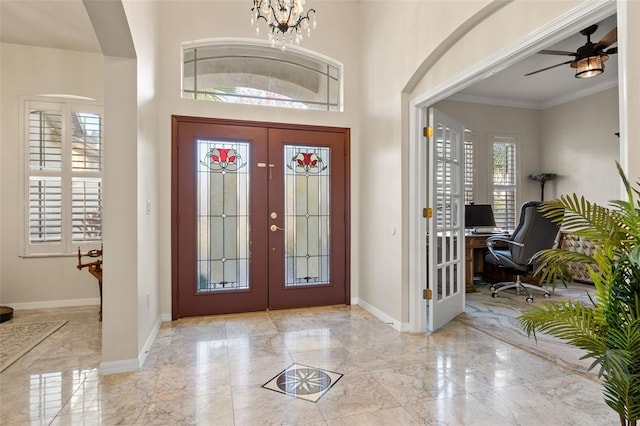 foyer entrance with french doors, crown molding, and ceiling fan with notable chandelier