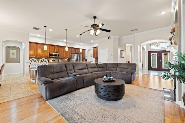 living room featuring crown molding, ceiling fan, light hardwood / wood-style flooring, and french doors