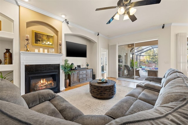 living room featuring crown molding, ceiling fan, a fireplace, and hardwood / wood-style floors