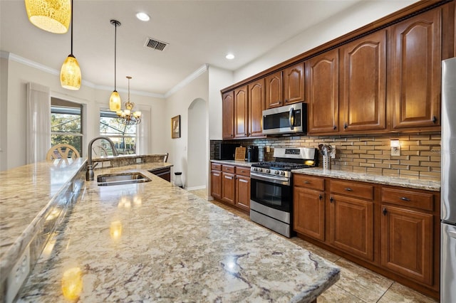 kitchen featuring sink, an inviting chandelier, stainless steel appliances, light stone counters, and decorative backsplash