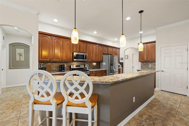 kitchen featuring tasteful backsplash, light stone counters, decorative light fixtures, and appliances with stainless steel finishes