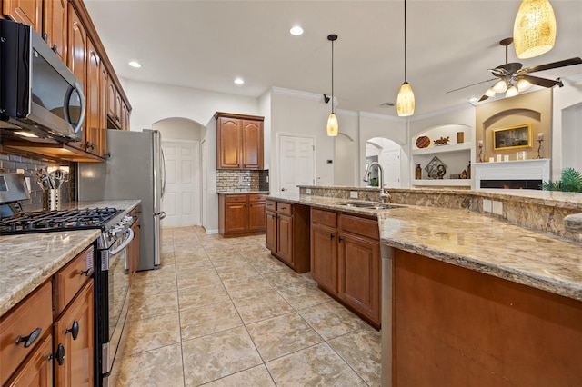 kitchen featuring appliances with stainless steel finishes, pendant lighting, sink, backsplash, and light stone counters