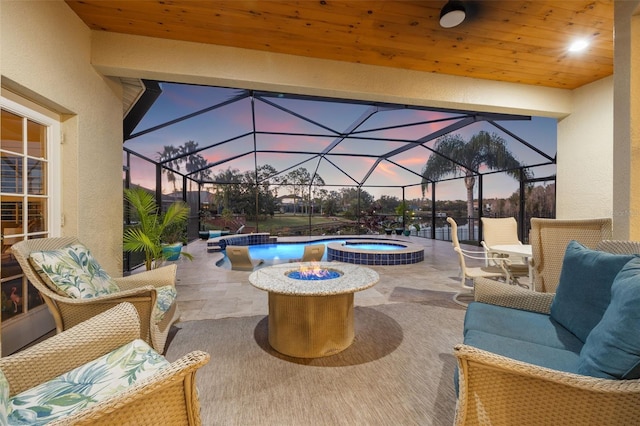 patio terrace at dusk featuring a swimming pool with hot tub, a lanai, and an outdoor living space